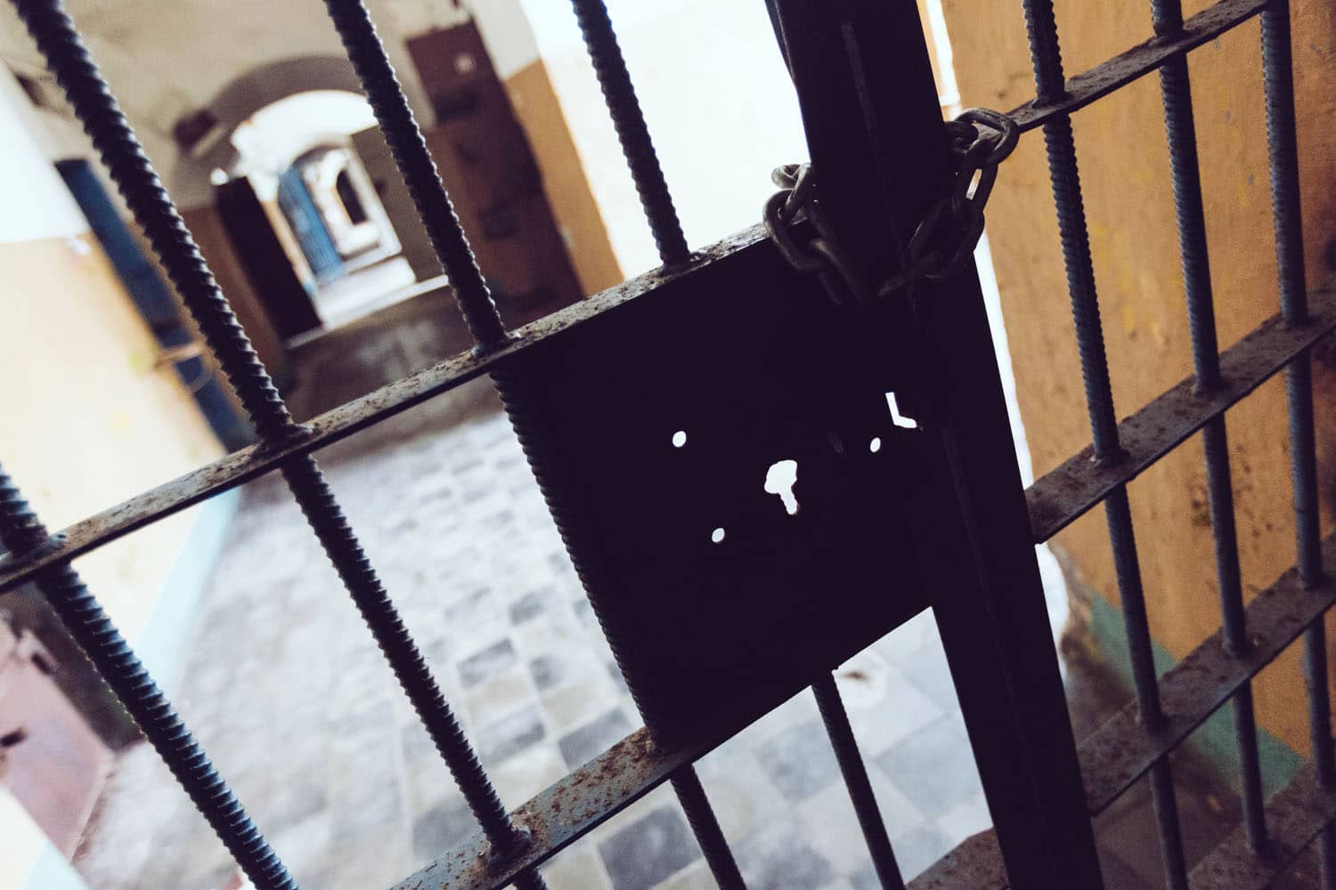 Is an escape room scary? Rusty padlock on a gate with a blurred corridor behind.