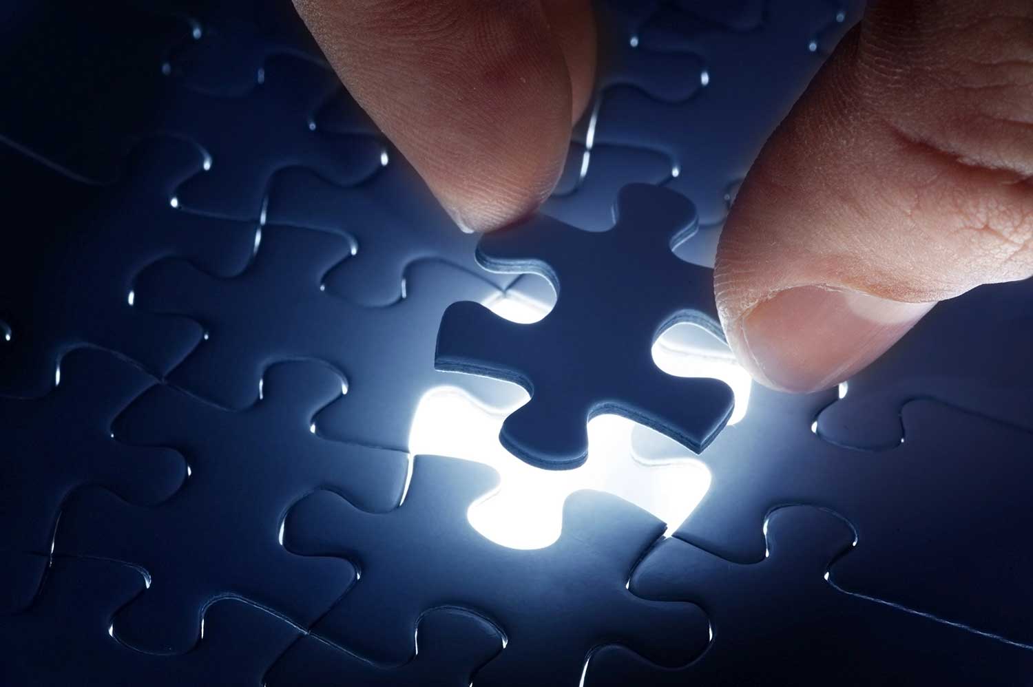 Person solving a complex puzzle with scattered pieces on a table