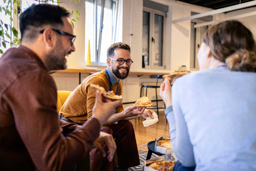 Coworkers sharing pizza during a casual corporate event
